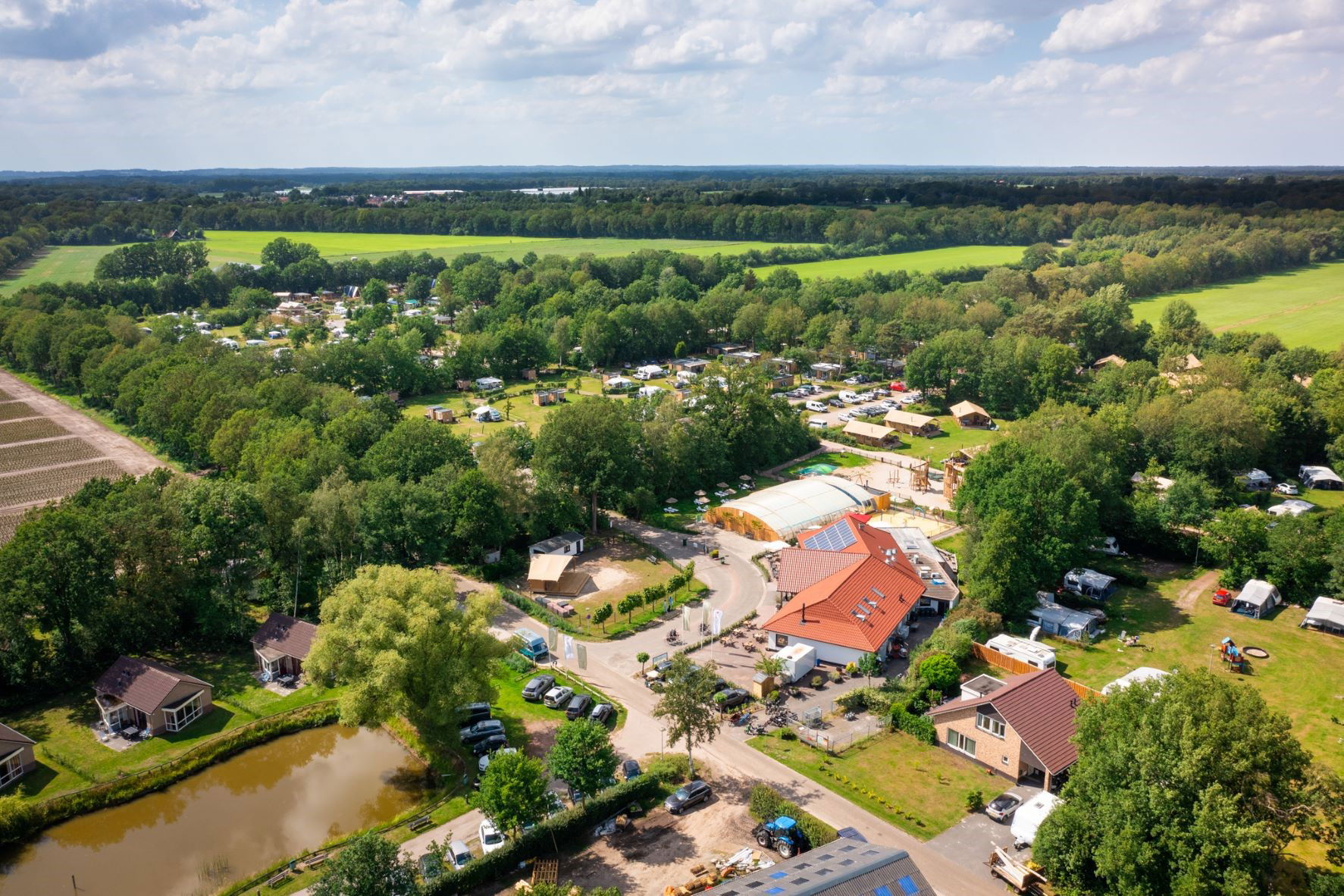 Von oben fotografierter Campingplatz umgeben von grünen Wiesen und Bäumen