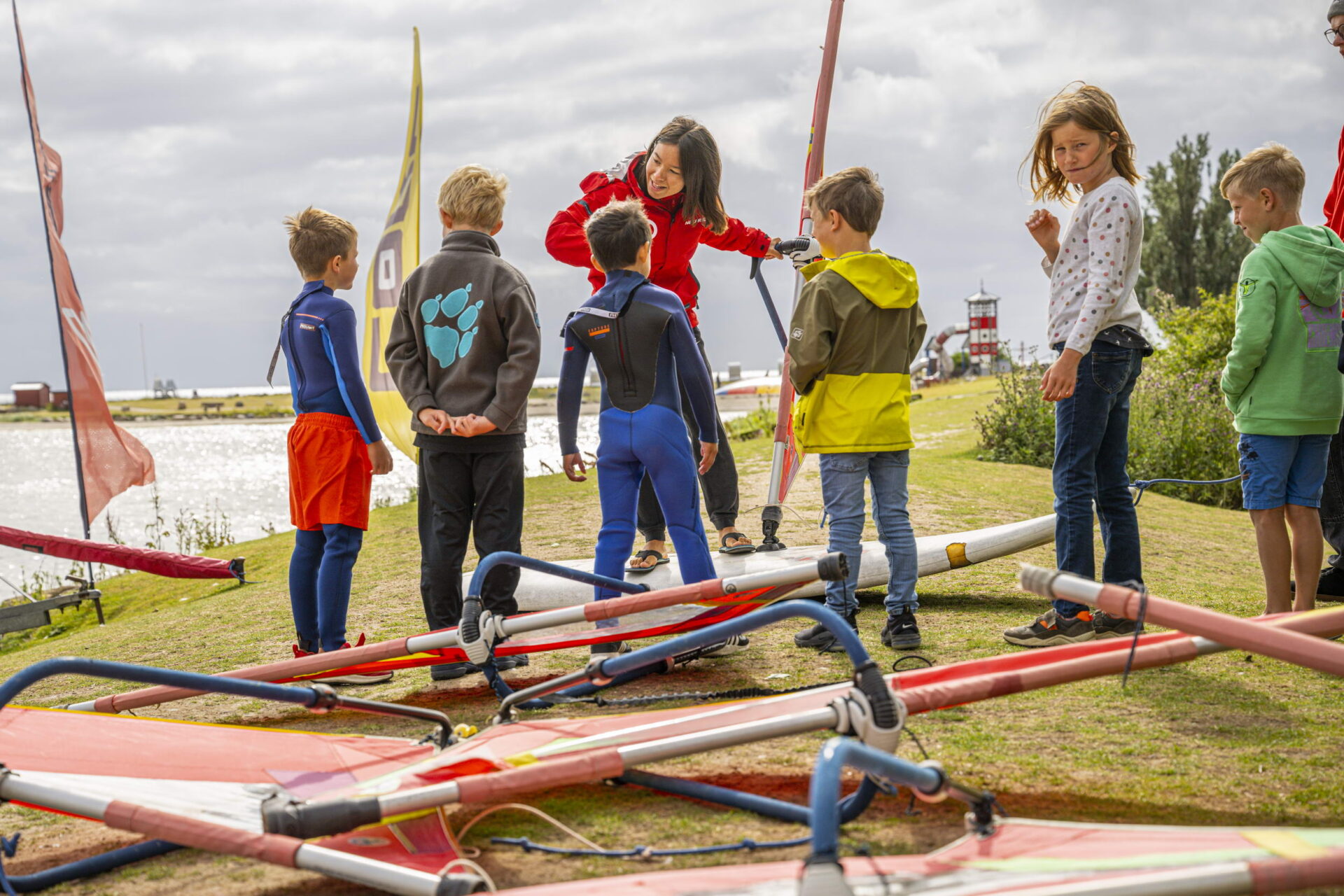 Viele Kinder mit einer Frau, die am Ufer surfen lernen