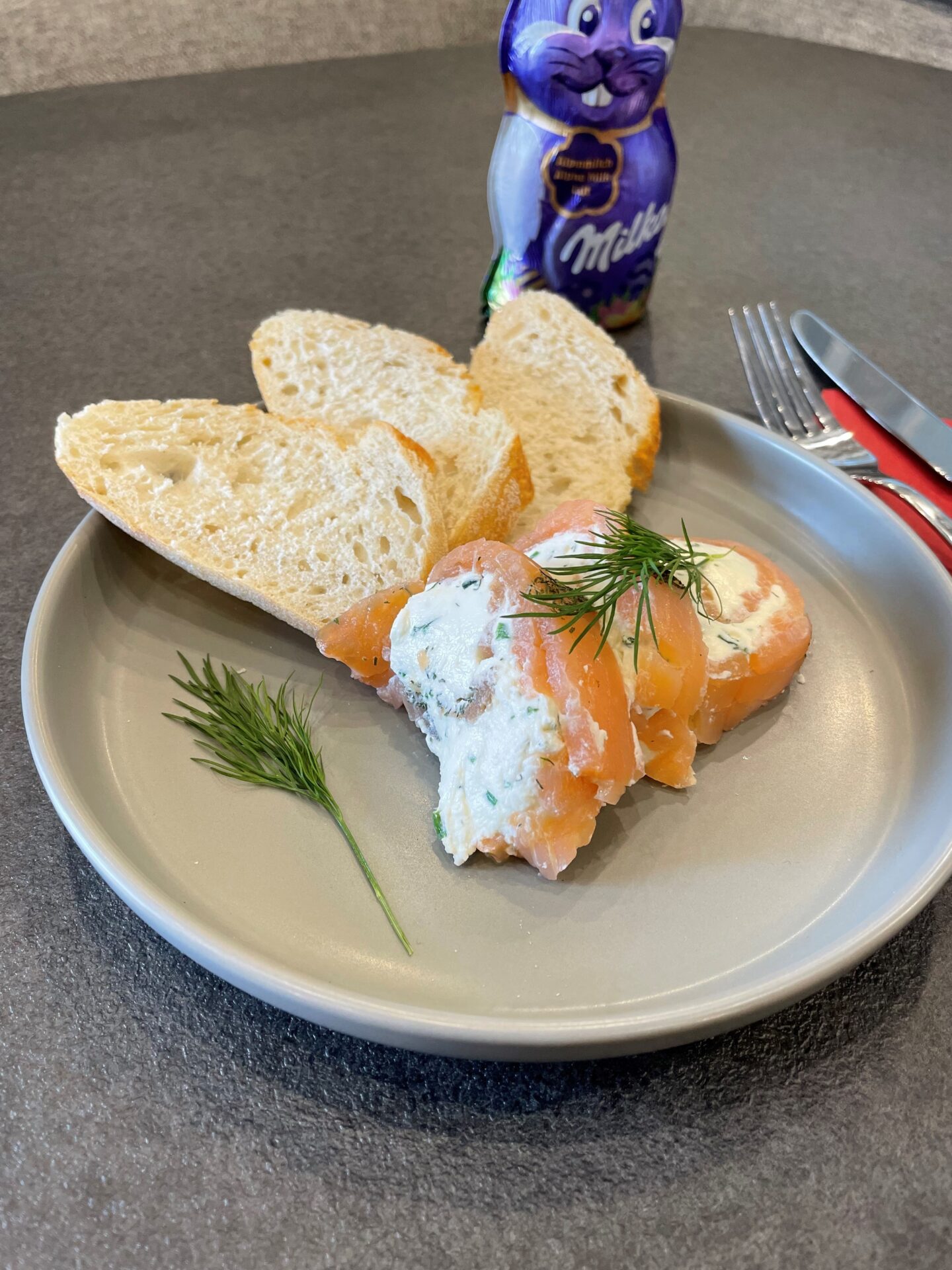 Teller mit Brot und Lachsröllchen und dahinter ein Schoko-Osterhase