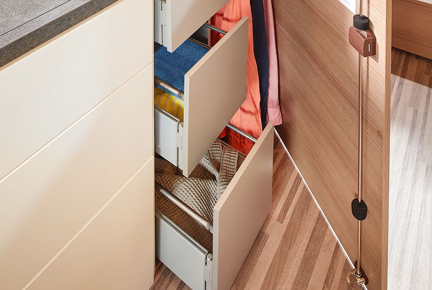 Beleuchteter Universal-Kleiderschrank unter dem Kühlschrank, links befinden sich drei innenliegende Schubkästen und rechts ein seperater Kleiderschrank mit einer Innenhöhe von 100 cm.